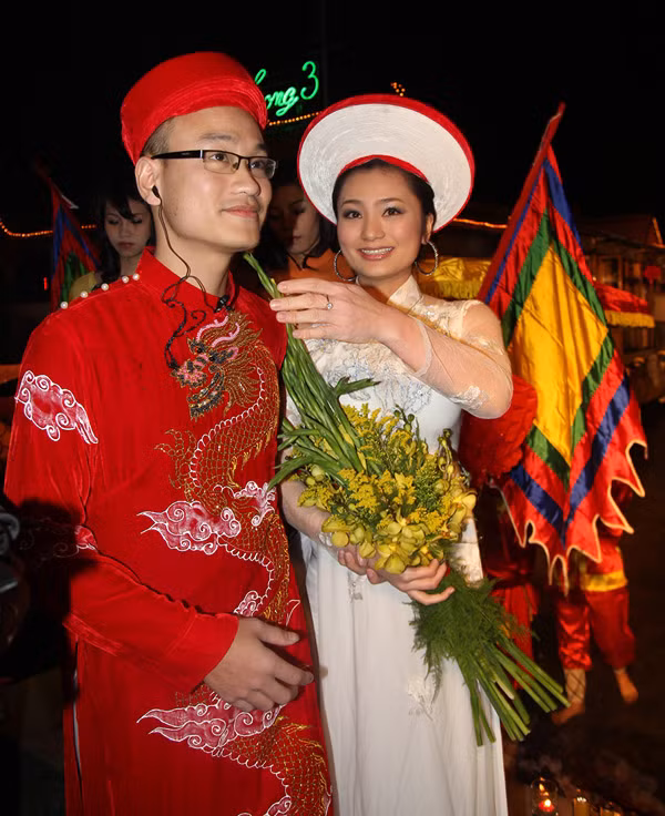 Là đạo diễn cho màn rước dâu bằng thuyền rồng nên Ngọc Linh phải đeo tai nghe để "chỉ đạo" mọi người. Khi thuyền đã cập bến, Diệu Hương nhắc ông xã tháo tai nghe để chuẩn bị cho nghi lễ tiếp theo. Ảnh: Quỳnh Như, Ngôi sao