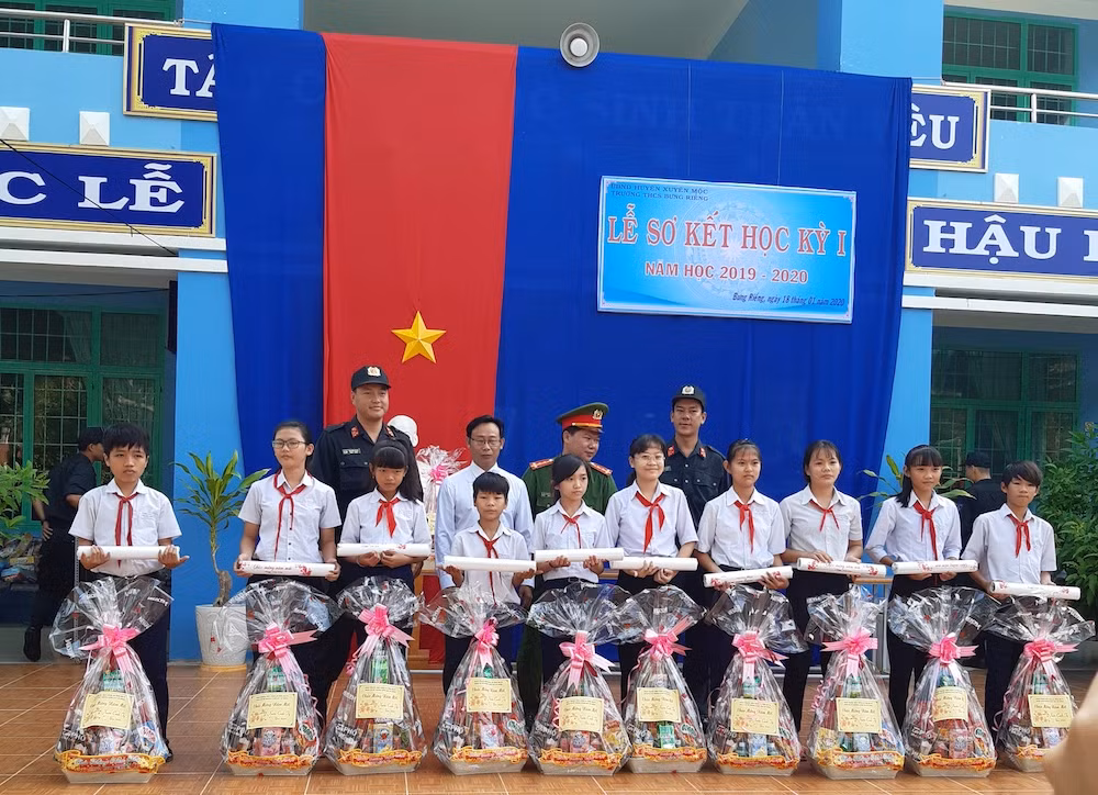Đồng chí Nguyễn Tứ Hải (bìa trái), Phạm Khắc Nhẫn (bìa phải) chụp ảnh lưu niệm với học sinh nhận quà xuân