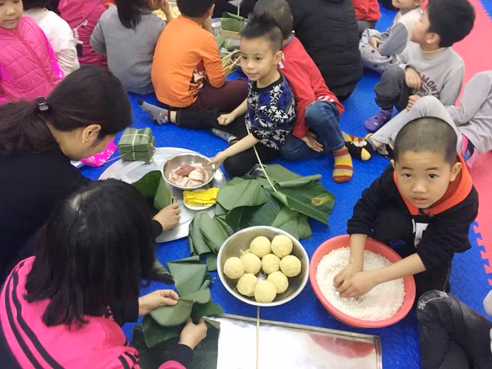 Học sinh trường Mầm non Bông Sen được hướng dẫn, tự tay gói bánh chưng (Ảnh: Lã Tiến)