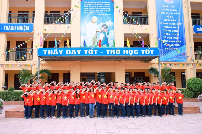 Các em học sinh và cô giáo chủ nhiệm cùng nhau mặc áo cờ đỏ sao vàng.