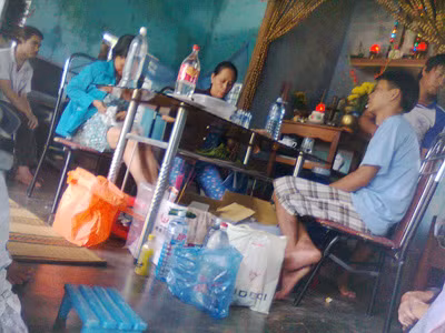 Bà Châu (ngồi giữa) đang “bốc thuốc“ cho người bệnh tại nhà. (ảnh chụp bằng điện thoại)