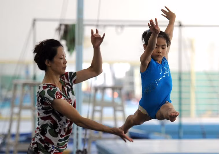 Huấn luyện viên giúp một bé gái tập luyện tại trung tâm thể thao ở Nam Kinh.