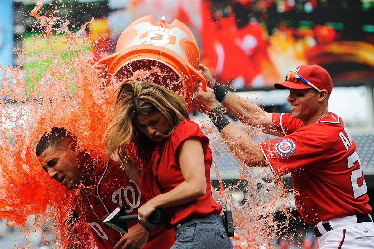 Ian Desmond (trái) dội xô nước đỏ lên mình đồng đội đang trả lời phỏng vấn đài MASN sau khi đội Washington Nationals giành chiến thắng trước Miami Marlins trên sân Nationals Park, Washington, Mỹ ngày 21/4.