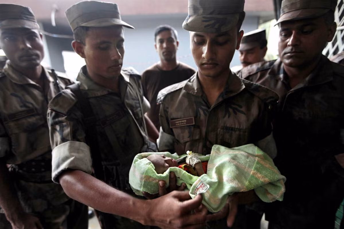 Các chiến sĩ biên phòng Bangladesh bế một bé gái bị bỏ rơi trên một chiếc thuyền ở Taknaf, Bangladesh ngày 22/6. Các chiến sĩ biên phòng Bangladesh bế một bé gái bị bỏ rơi trên một chiếc thuyền ở Taknaf, Bangladesh ngày 22/6.