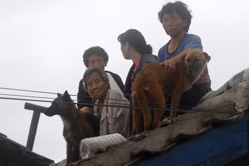 Người dân chờ được giải cứu trên mái của một ngôi nhà ở vùng ngoại ô của Anju. Người dân chờ được giải cứu trên mái của một ngôi nhà ở vùng ngoại ô của Anju.