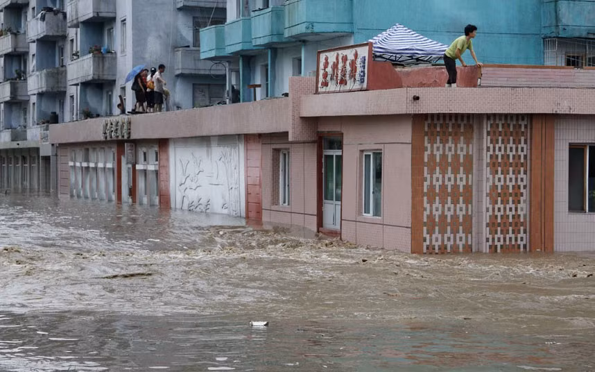 Người dân chờ đợi được giải cứu trên mái của một tòa nhà bị ngập nước trong thành phố Anju. Người dân chờ đợi được giải cứu trên mái của một tòa nhà bị ngập nước trong thành phố Anju.