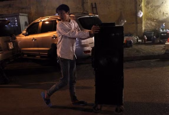 Nam thanh niên đẩy thùng loa gần một quán ăn trên hè phố ở Hà Nội ngày 16/12/2010
