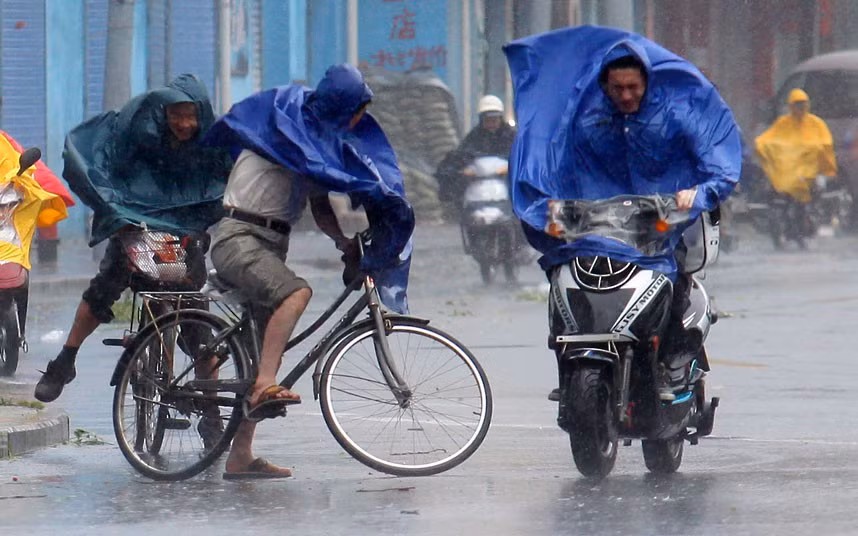 Người đi xe đạp, xe máy vật lộn với gió bão. Người đi xe đạp, xe máy vật lộn với gió bão.