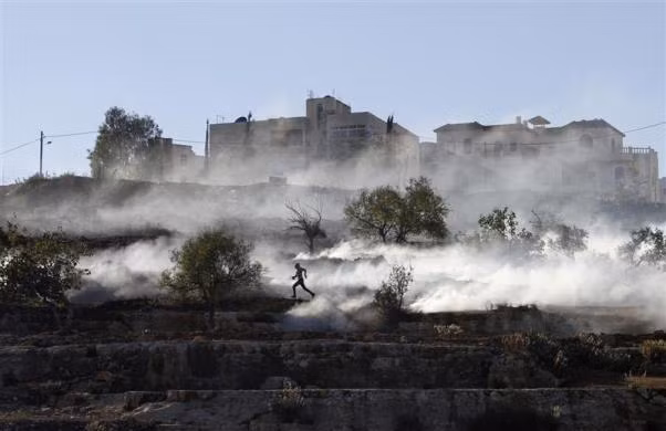 Một người Palestine chạy trốn hơi cay của Quân đội Israel trong cuộc đụng độ tại Gaza hôm 15/11. Một người Palestine chạy trốn hơi cay của Quân đội Israel trong cuộc đụng độ tại Gaza hôm 15/11.