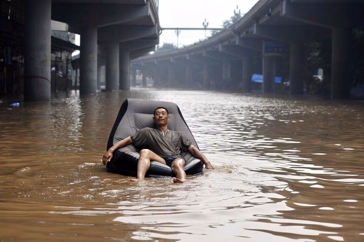 Một người đàn ông ngồi trên chiếc ghế hơi di chuyển trên con phố ngập nước ở Trùng Khánh, Trung Quốc ngày 25 tháng 7. Một người đàn ông ngồi trên chiếc ghế hơi di chuyển trên con phố ngập nước ở Trùng Khánh, Trung Quốc ngày 25 tháng 7.