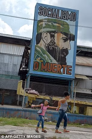 Trẻ em cùng mẹ đi qua một bức chân dung của Chủ tịch Fidel Castro.