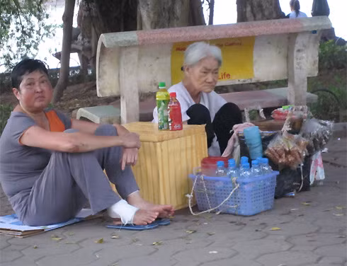 Ở một góc khác của Hà Nội, bên chiếc ghế đá ven hồ Hoàn Kiếm, một cụ bà ngồi bệt ngay vỉa hè, bán vài chai nước, vài gói kẹo mỗi buổi chiều chỉ để kiếm vài đồng bạc lo cho ngày hai bữa cơm tằn tiện.