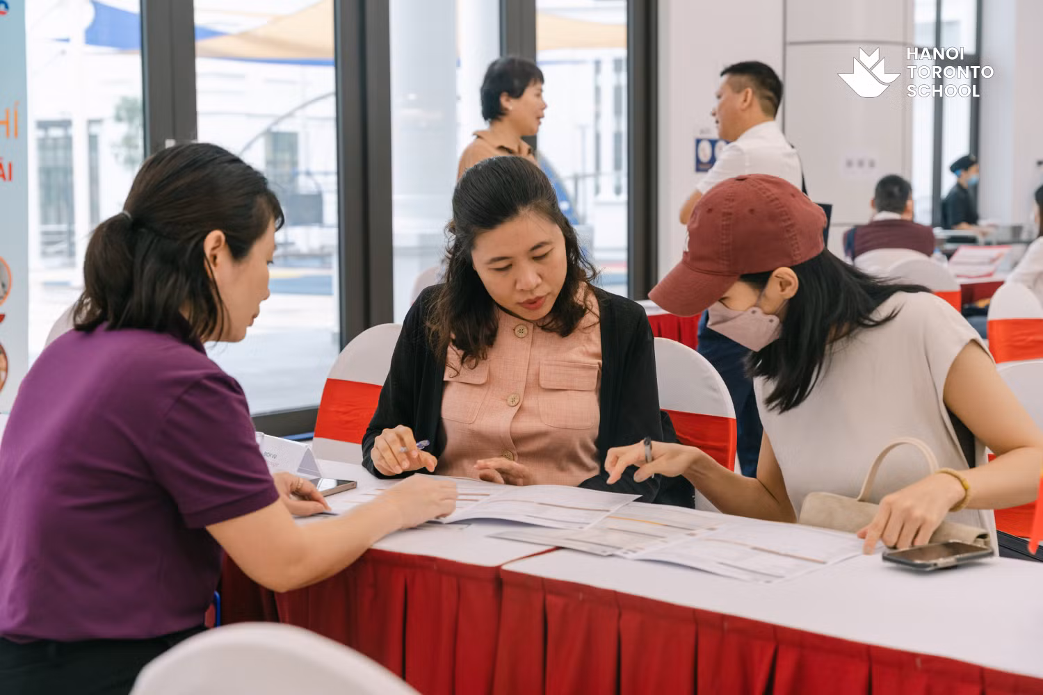Một phụ huynh đang thực hiện các thủ tục đăng ký học cho con tại Ngày hội thông tin – "Hành trình vững bước tương lai"