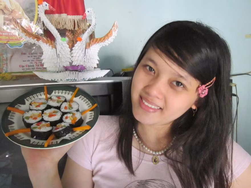 "Từ nhỏ mình đã rất thích đọc truyện tranh và xem phim hoạt hình Nhật Bản, vì vậy mà mình thích luôn cả những nét văn hóa, truyền thống lẫn ẩm thức của xứ sở hoa anh đào. Nhắc đến món ăn Nhật Bản thì chắc hẳn mọi người đều nghĩ ngay đến món Sushi nổi tiếng. Có rất nhiều loại Sushi khác nhau, và dĩ nhiên món nào cũng rất cầu kỳ. Dễ làm nhất có lẽ là Sushi cơm cuộn, chỉ cần một tí khéo tay là có thể làm ra món Sushi với nhiều loại nhân khác nhau. Để làm nhân Sushi, mình thường hấp cà rốt, đậu que để giữ được chất dinh dưỡng, màu sắc cũng như vị Umami tự nhiên trong rau củ, ngoài ra còn có trứng chiên và xúc xích. Tất cả thức ăn này nằm trong nắm cơm trắng dẻo, bên ngoài là lớp rong biển mỏng dai, tạo nên một hương vị rất riêng, rất Nhật Bản. Mình luôn muốn được thưởng thức thêm nhiều loại Sushi khác, và đặc biệt, nếu có thể, mình muốn được một lần đến đất nước Nhật Bản, thưởng thức món Sushi do chính tay đầu bếp Nhât chế biến, chắc hẳn sẽ rất khác, và ...ngon hơn mình làm rất nhiều"